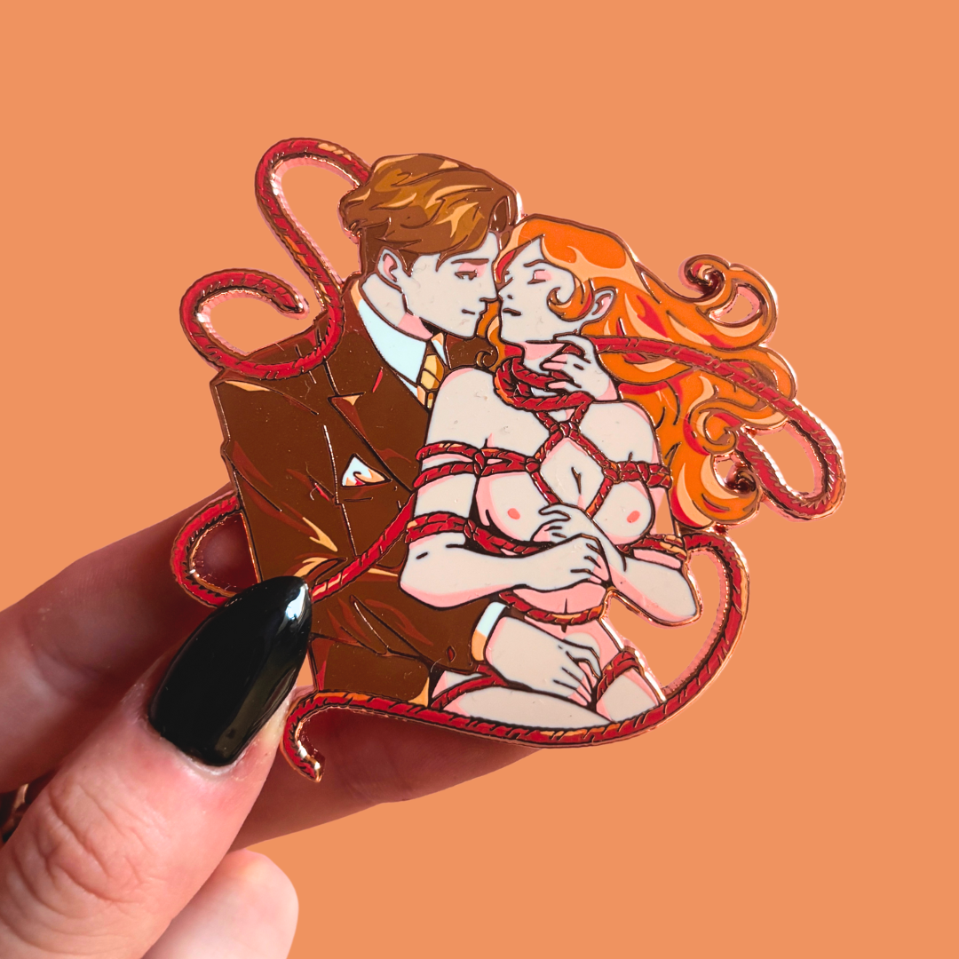 Pin of a couple in a romantic pose with red ropes on an orange background.