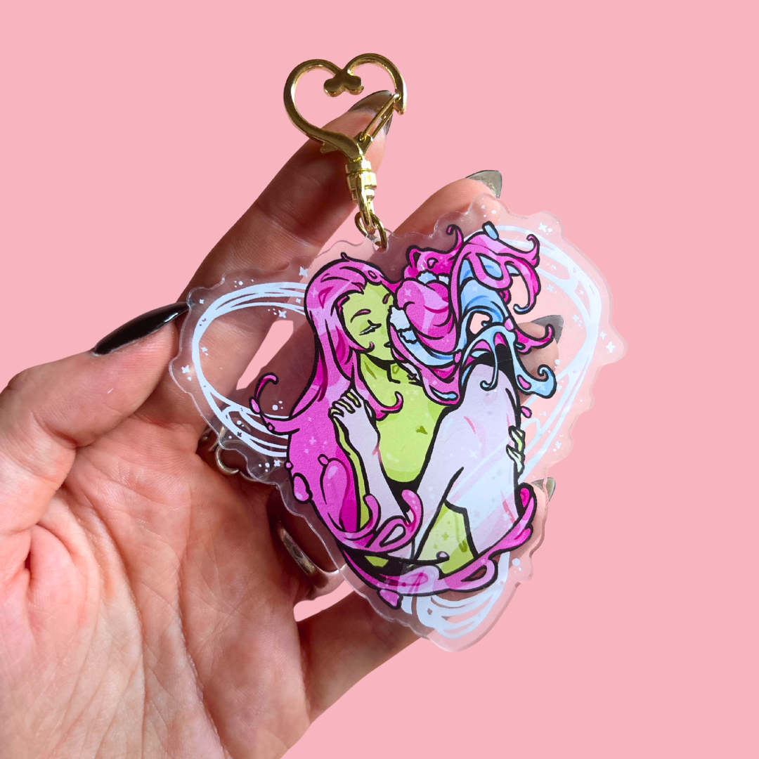 Keychain with colorful design held by a hand against a pink background