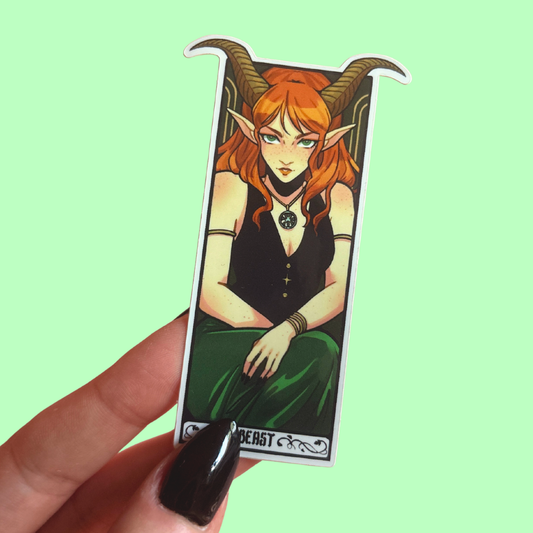 Sticker of a fantasy character with red hair and horns held against a light green background