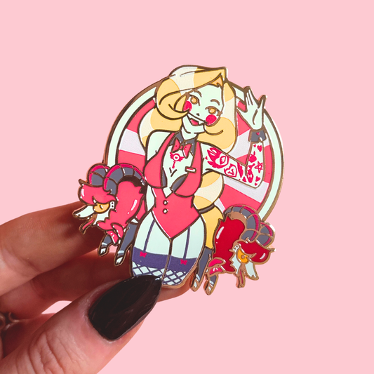 Colorful cartoon character pin held by a hand on a pink background