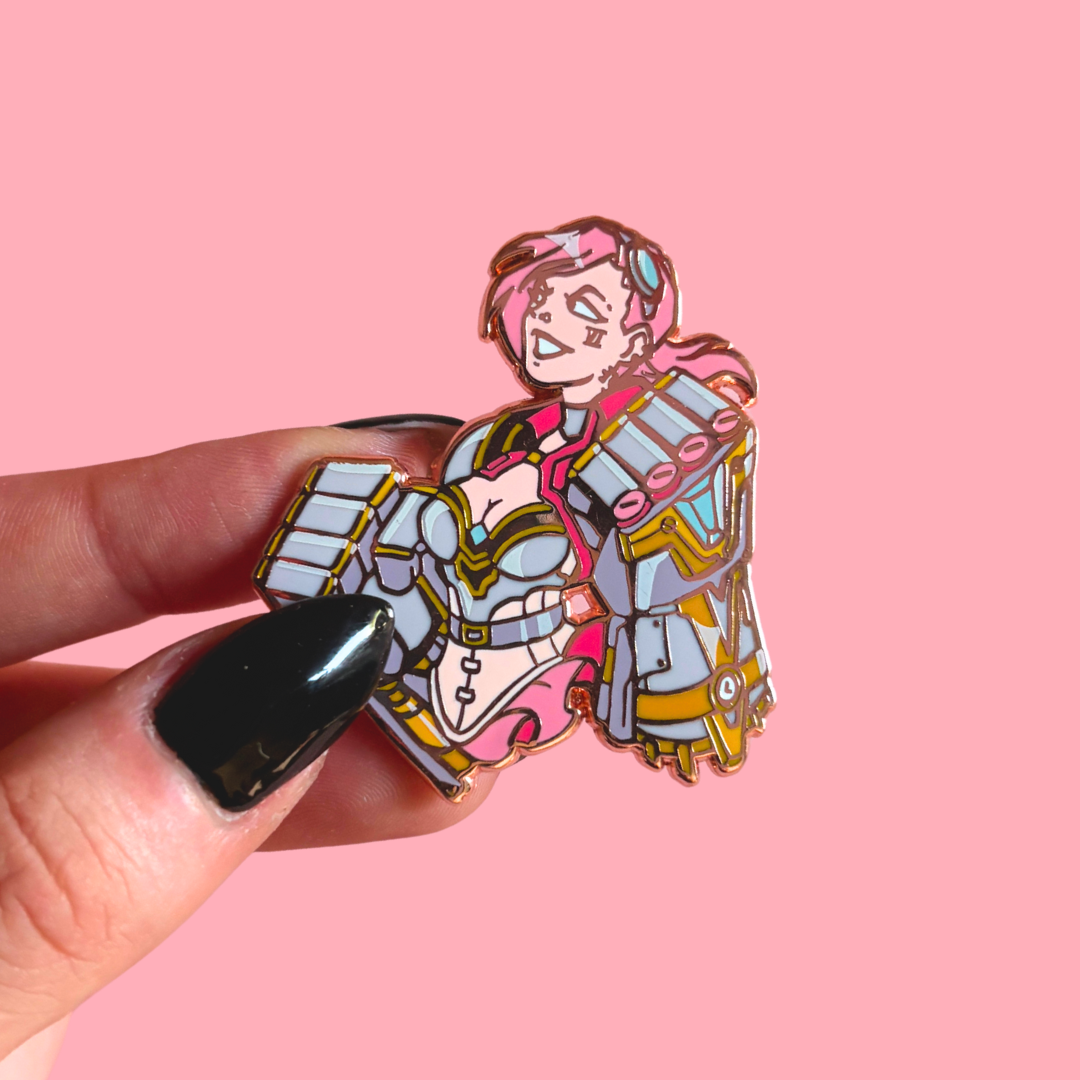 Pin with cartoon character design held by a hand against a pink background