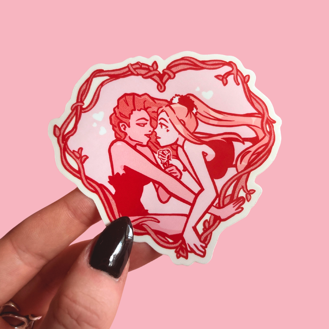 Sticker of two women embracing with a heart-shaped frame held by a hand on a pink background
