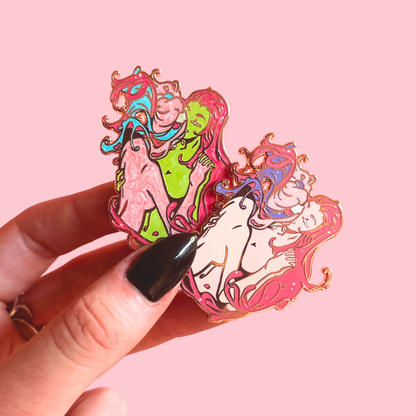Colorful character-shaped pins. One in green and pink, the other in just pink colourway held by a hand against a pink background