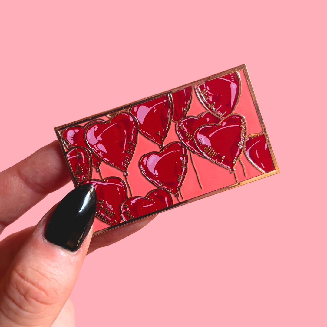 Rectangle Pin with helium heart balloons with pink palette held by a hand against a pink background