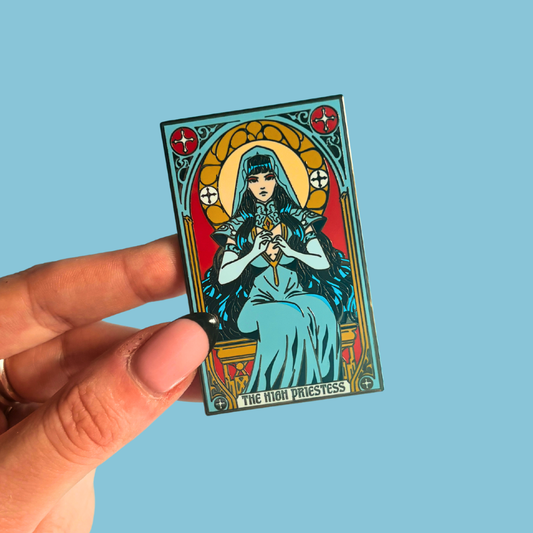 Hand holding a tarot card pin featuring 'The High Priestess' against a blue background