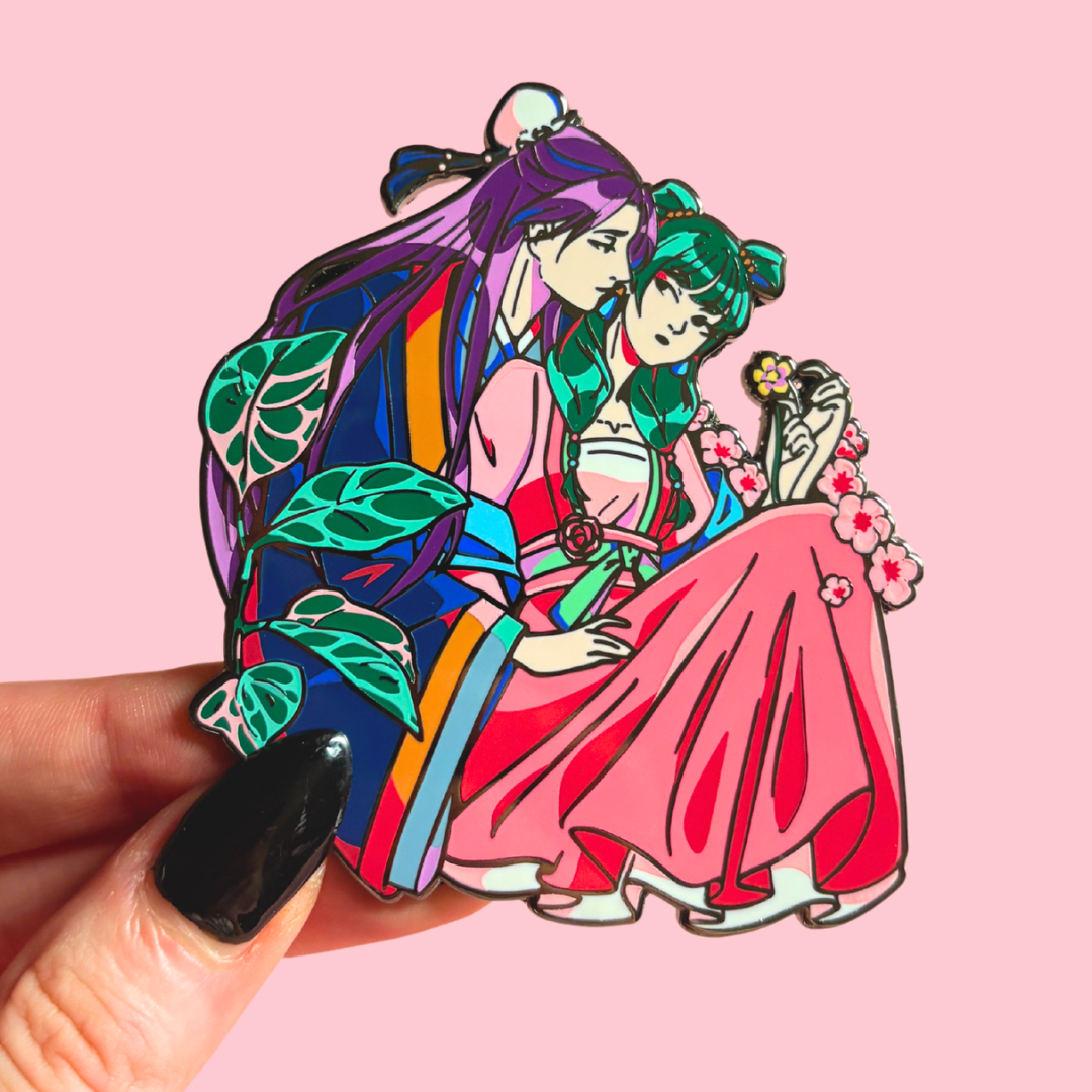 Colorful enamel pin of two characters in traditional attire against a pink background