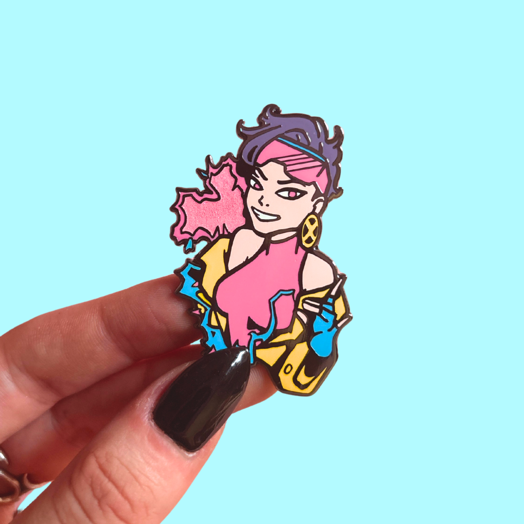 Colorful character pin held by a hand against a light blue background