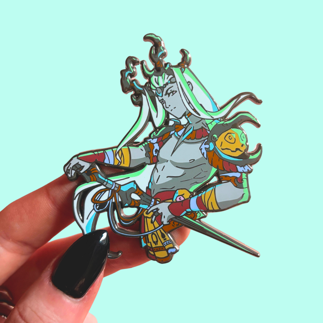 Colorful character pin design held by a hand against a light blue background