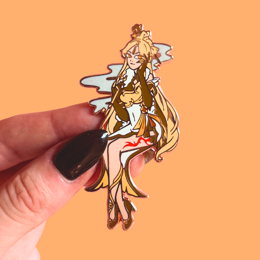 Hand holding a reflective enamel pin of an anime-style character against an orange background