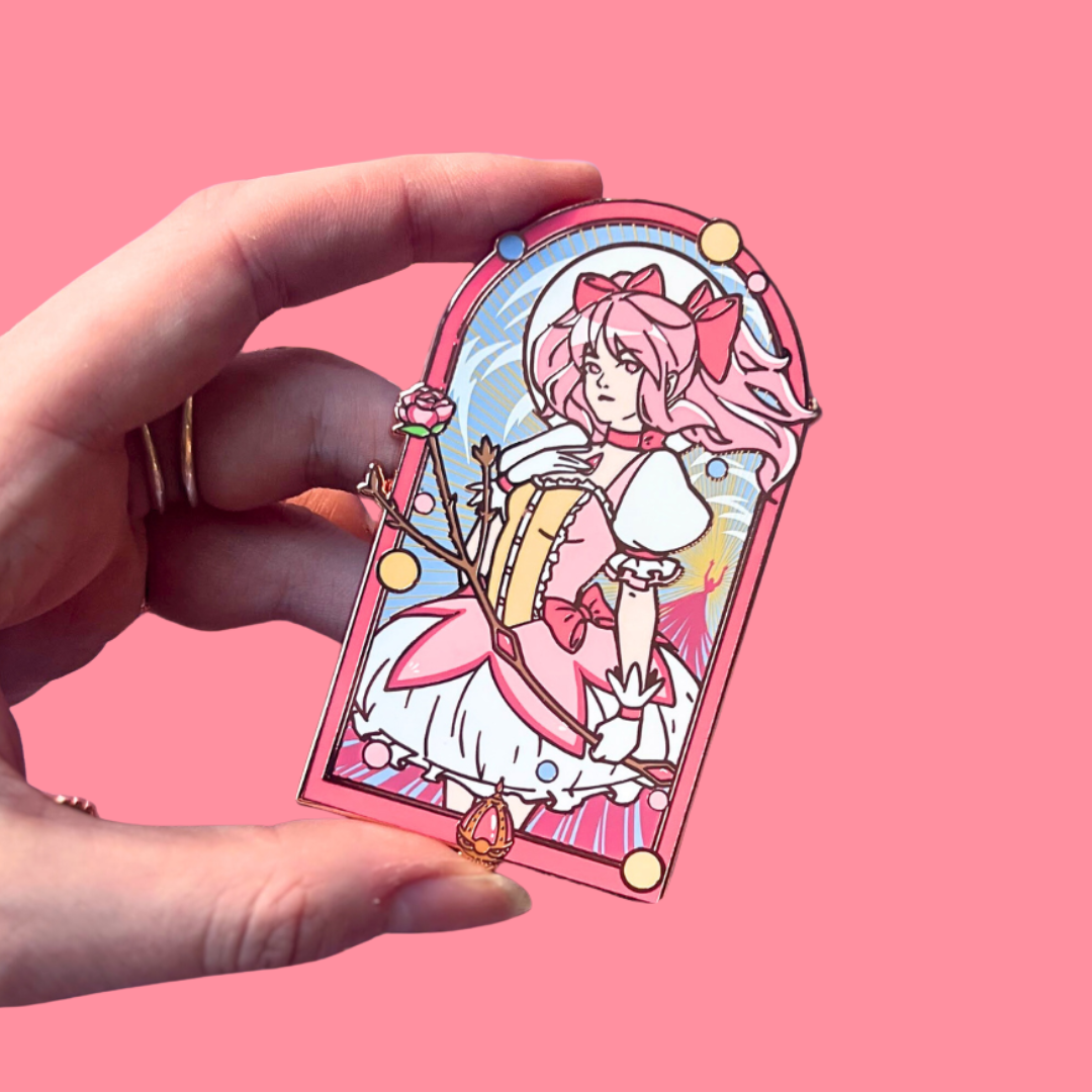 Hand holding a colorful pink pin of a character with a pink background