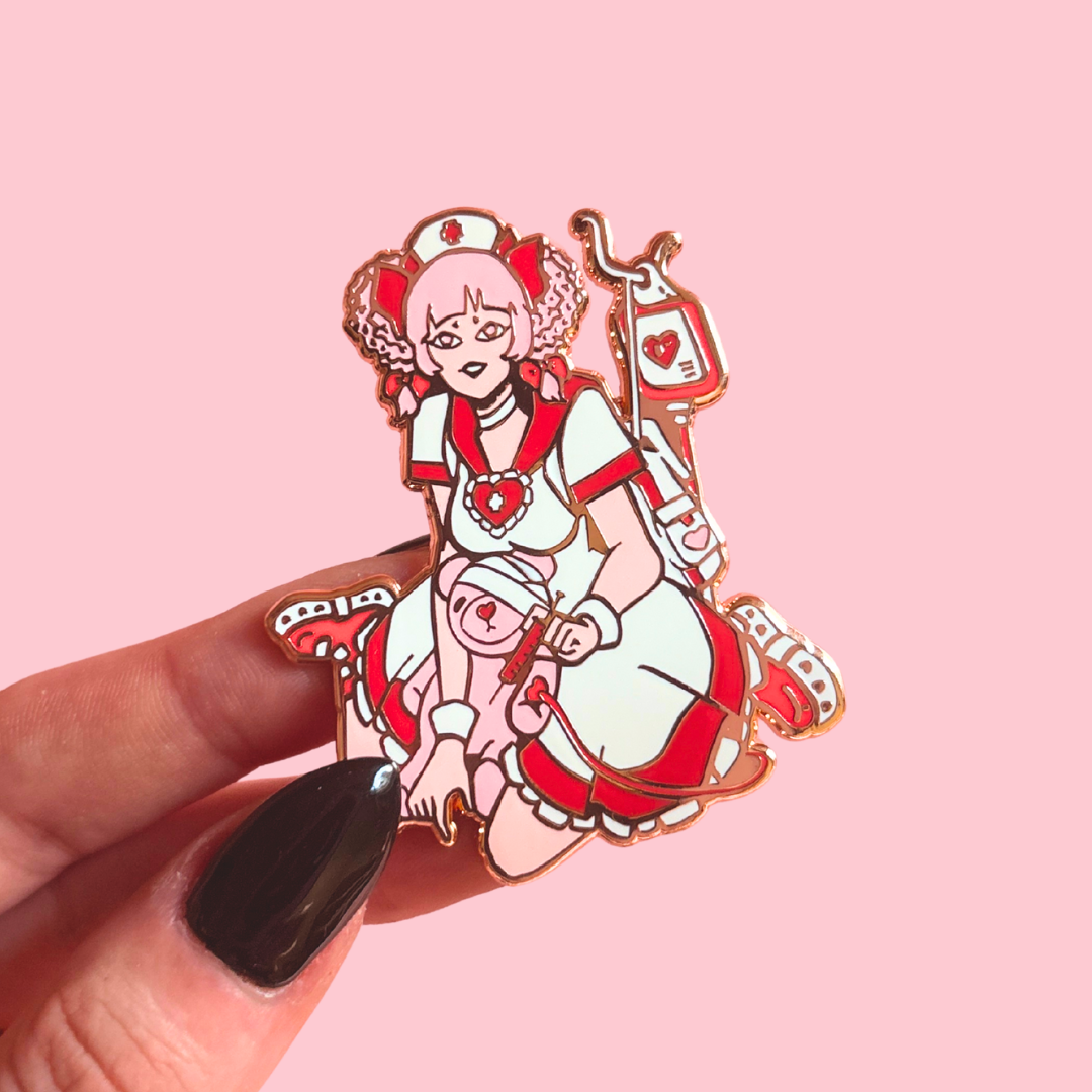 Enamel pin of a character in a nurse outfit held by a hand on a pink background