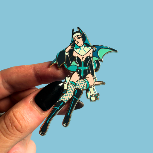 Pin with a stylized character in a bat-themed outfit held by a hand against a blue background