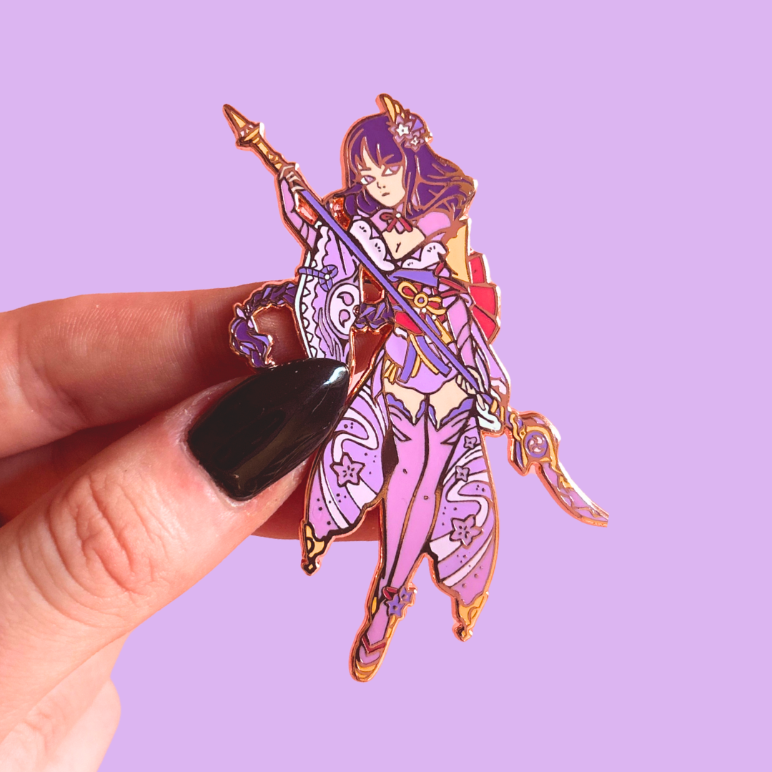 Colorful purple character pin held by a hand against a purple background