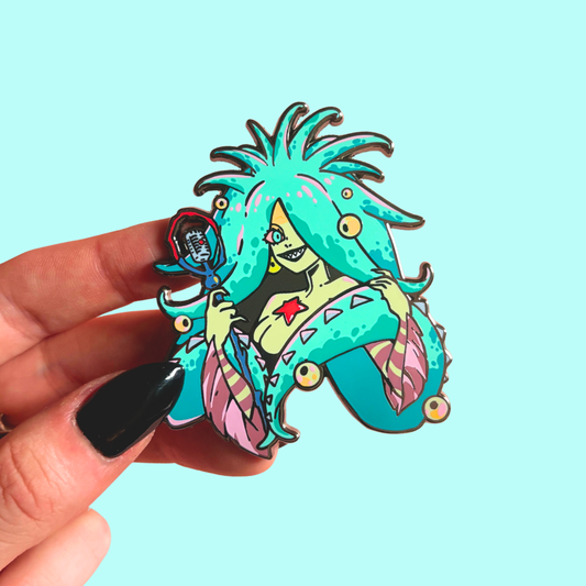 Colorful character pin held by a hand against a light blue background