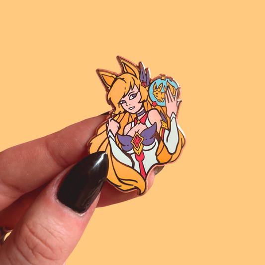 Animated character pin held by a hand with black nail polish against a yellow background
