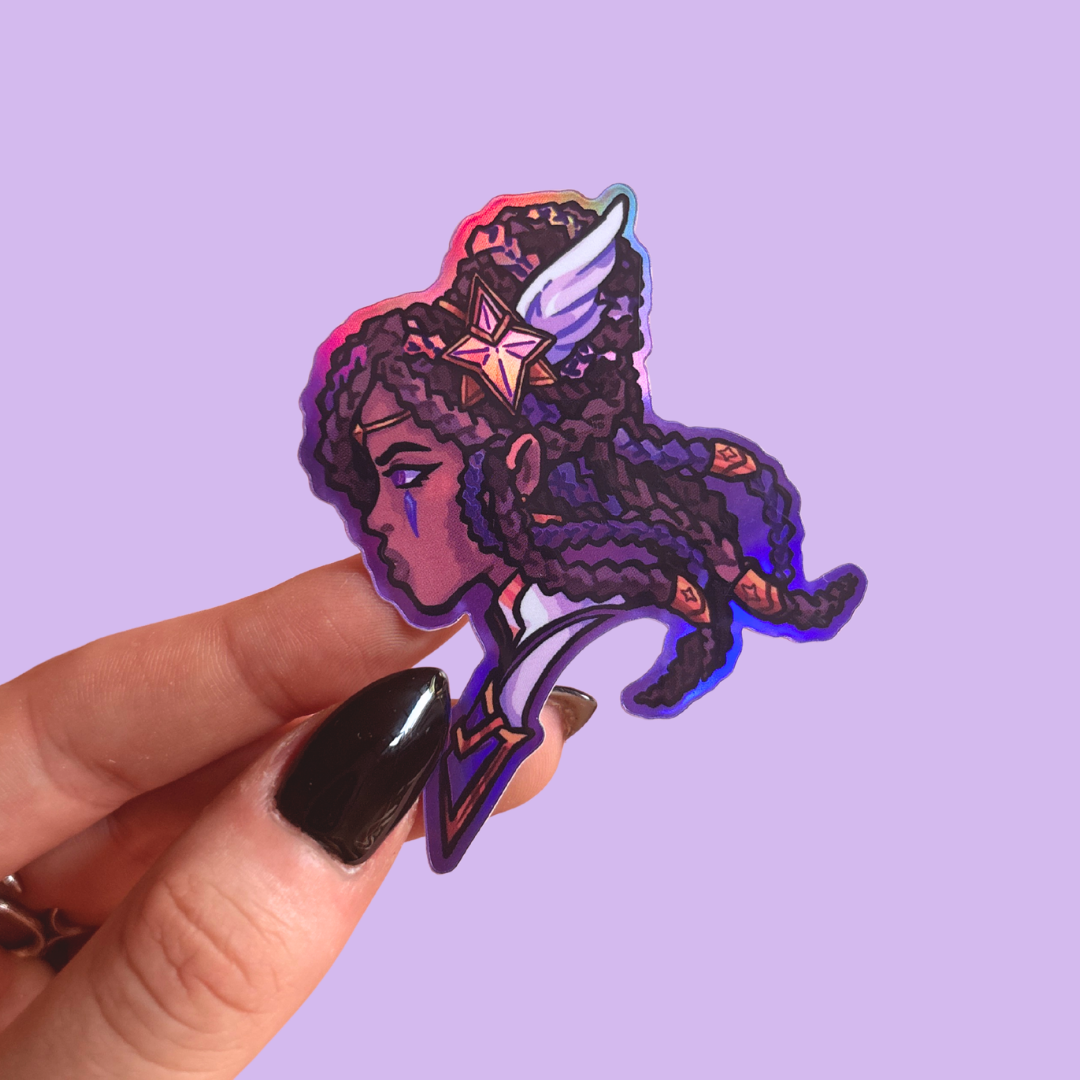 Holographic sticker of a person with wings on head held by a hand against a purple background