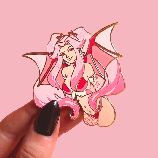 Succubus character pin with pink hair and wings held by a hand on a pink background