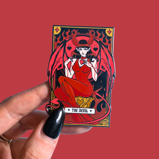 Pin featuring 'The Devil' tarot card design held by a hand against a red background
