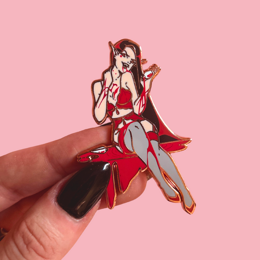 Enamel pin of a stylized female figure in a red outfit held against a pink background