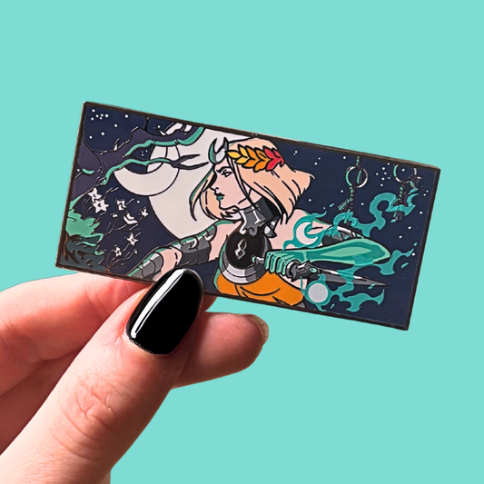 Hand holding a rectangular enamel pin with a stylized illustration of a woman against a starry night sky on a teal background.